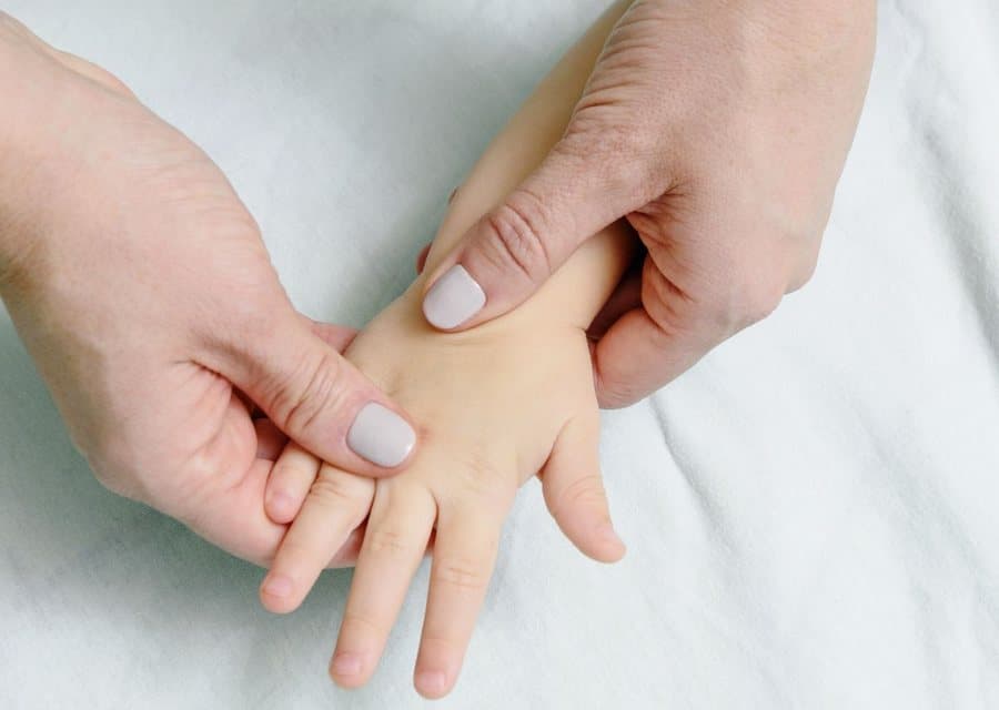 Mains d'adulte massant doucement la main d'un enfant
