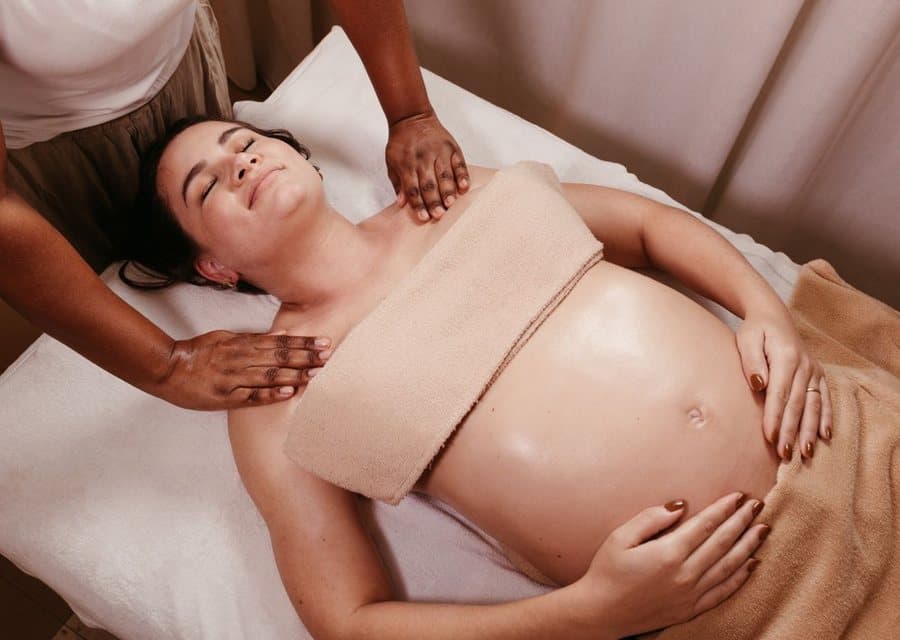 Massage doux du ventre d'une femme enceinte, allongée sur une table